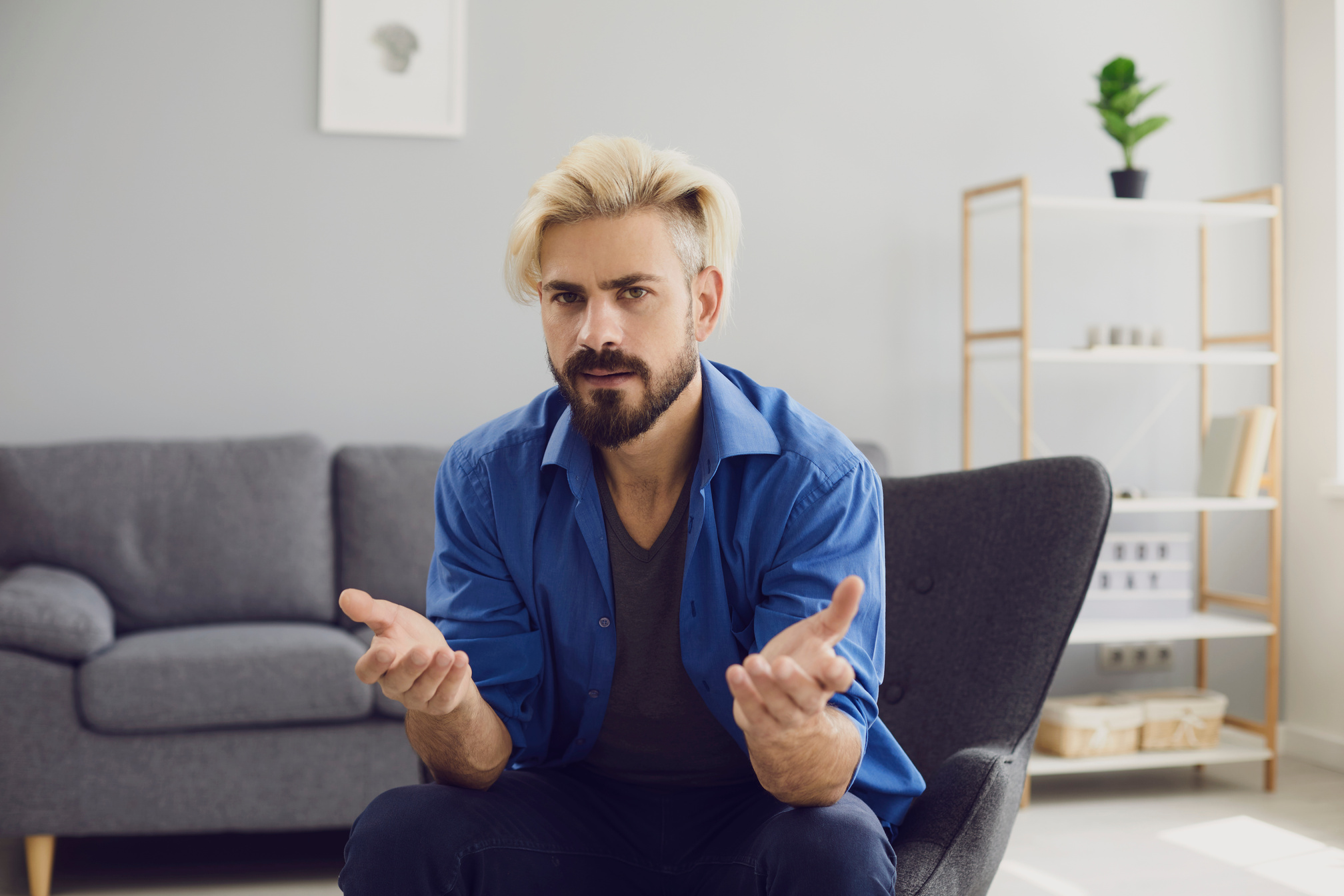 Confused Hipster Man Sitting in Armchair at Home
